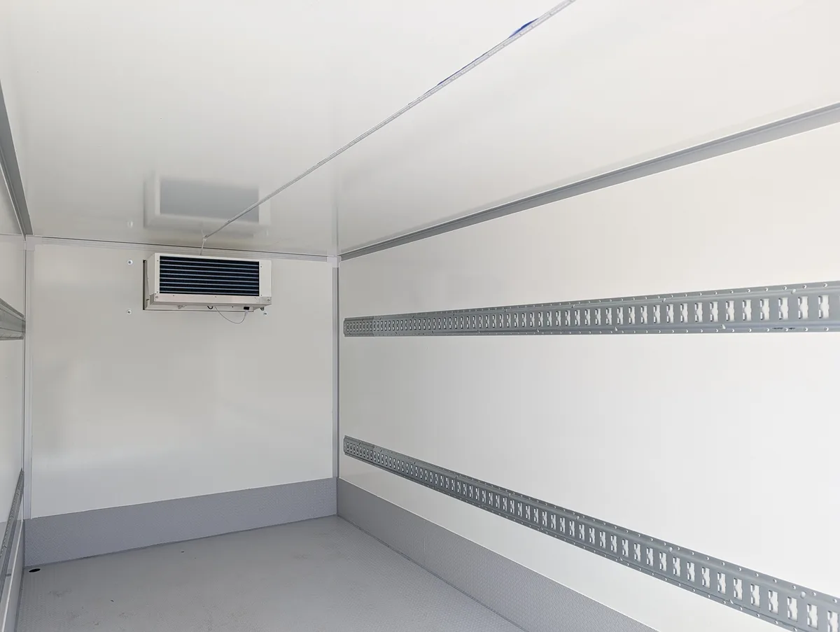 Trailer interior with white insulated panels, two rows of E-track on each wall, and a ceiling-mounted evaporator