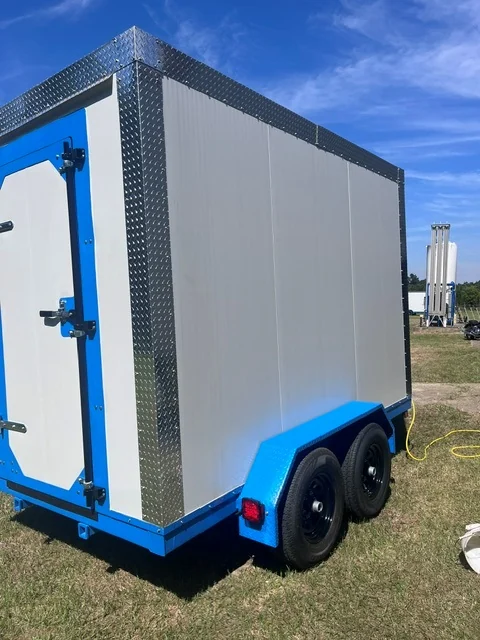 Rear three-quarter view of the trailer with a power cord running to an ordinary outlet